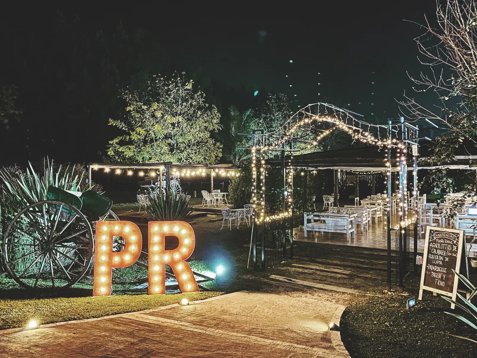 Jardín iluminado de noche con letras luminosas PR en Pasta Rossa Canning