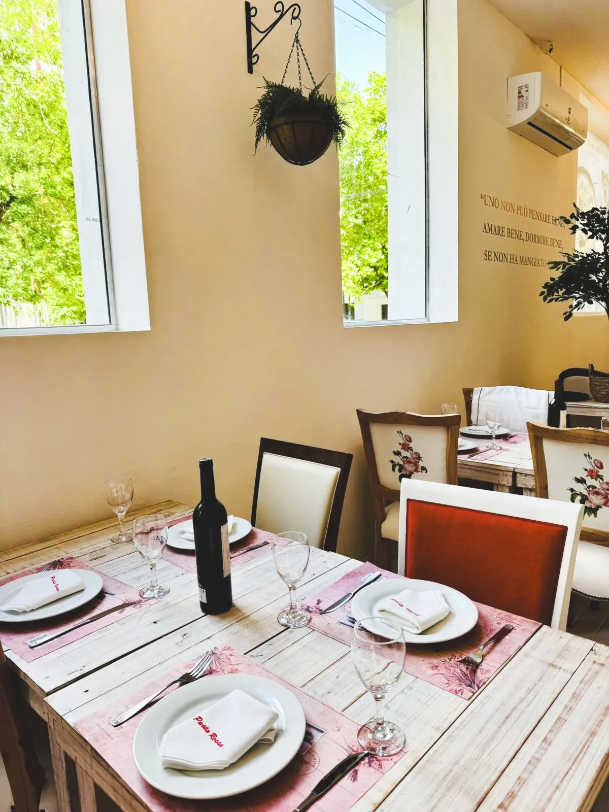 Mesas servidas junto a ventanales en Pasta Rossa La Plata