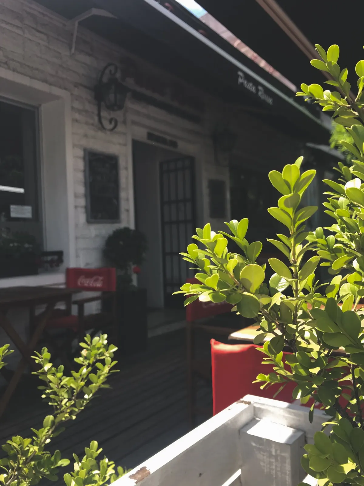 Galería exterior con plantas en la entrada de Pasta Rossa Lomitas