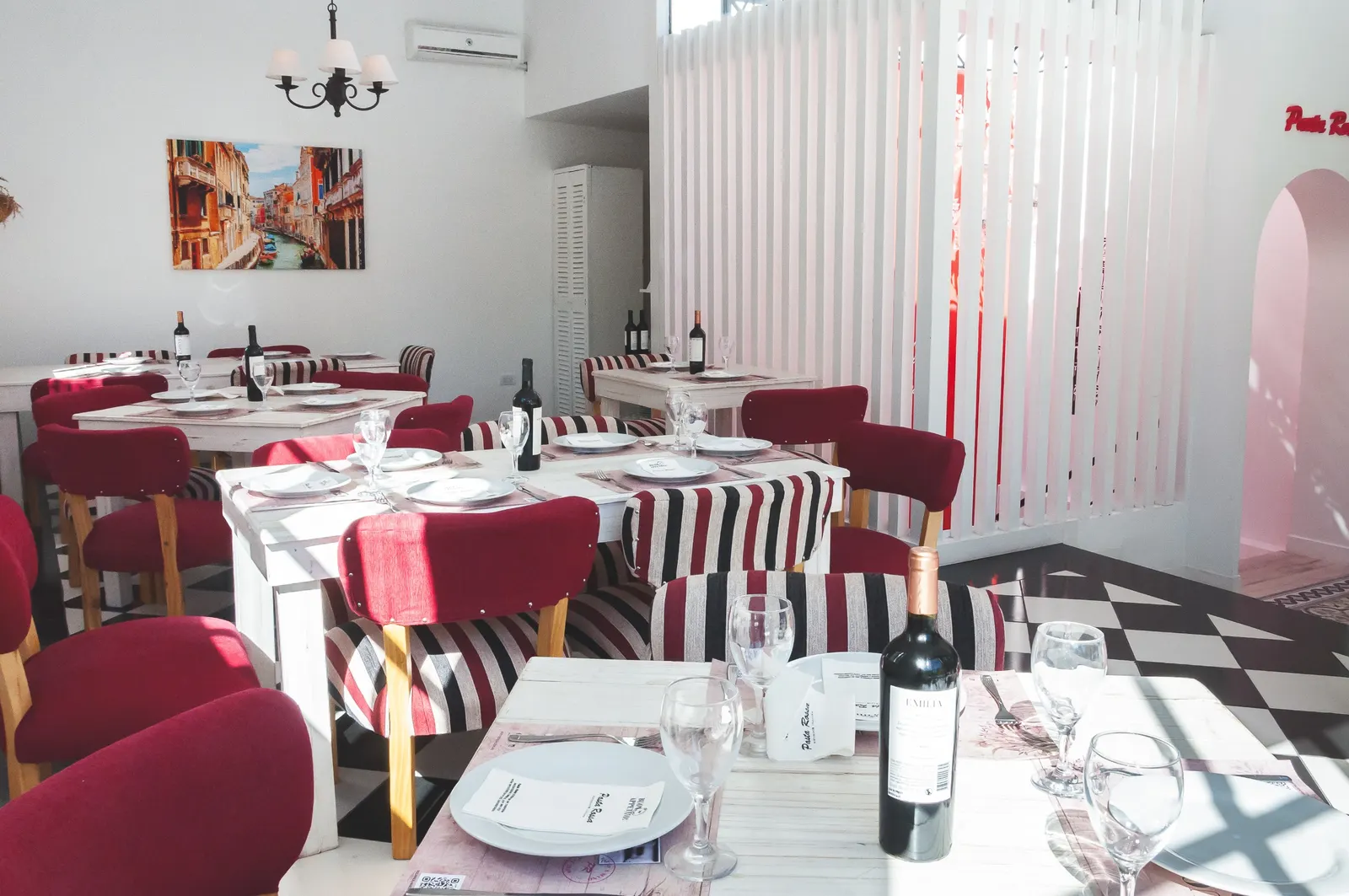 Salón con sillas rojas y mesas servidas en Pasta Rossa Quilmes