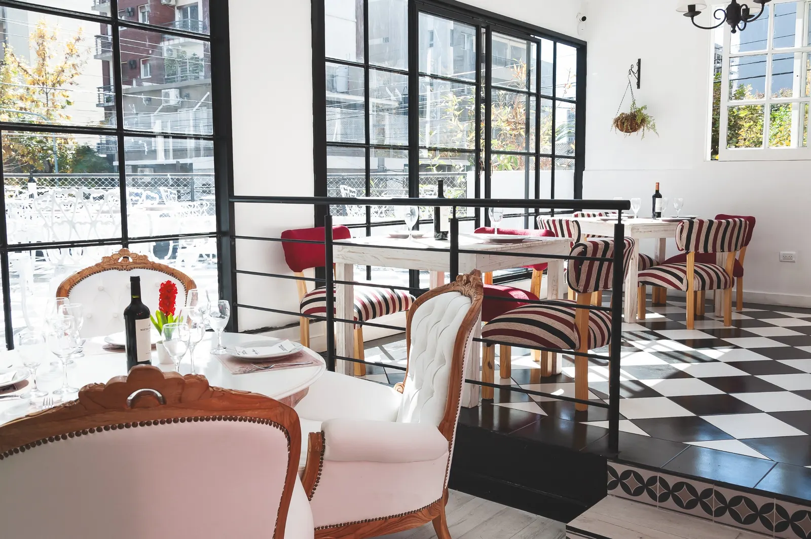 Salón con ventanales, piso a cuadros y sillas tapizadas en Pasta Rossa Quilmes