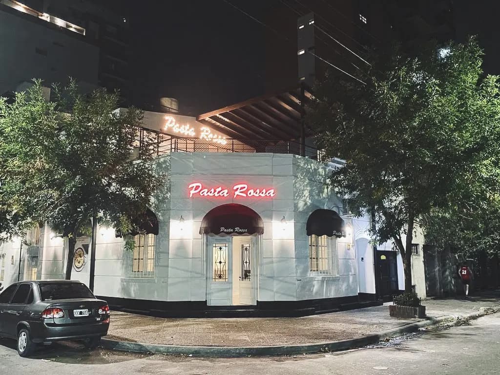 Fachada blanca de Pasta Rossa Quilmes iluminada de noche