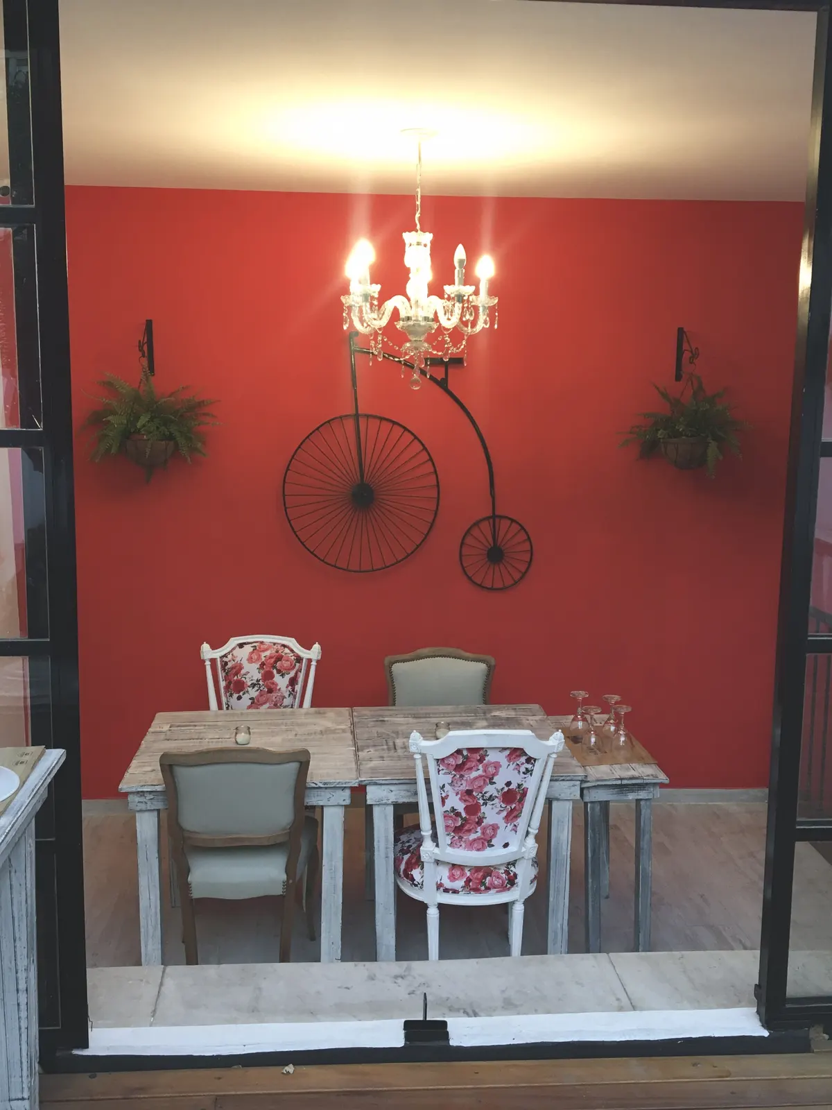 Mesa junto a una pared roja con araña y bicicleta antigua en Pasta Rossa Ramos Mejía